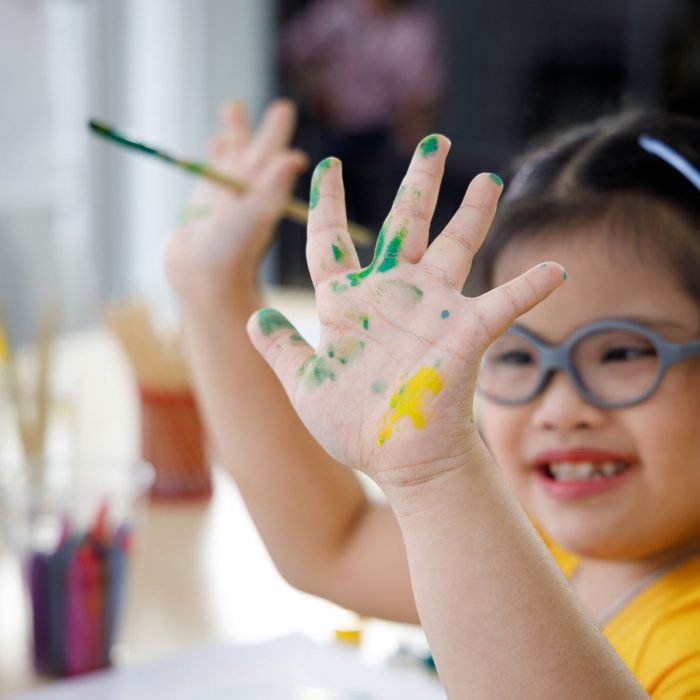 little girl holding up her paint colored hands