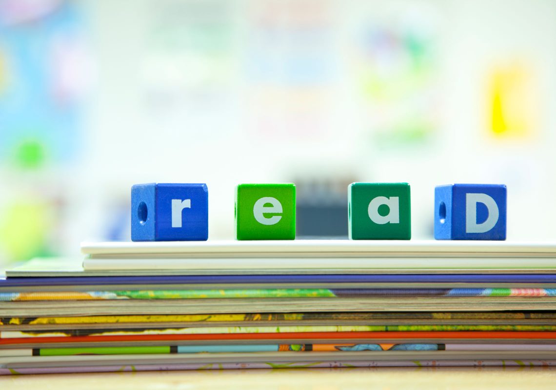 blocks that spell "read" on a stack of picture books